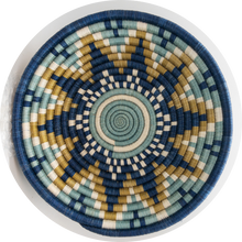 Load image into Gallery viewer, The Sunrise Handwoven Basket by Her Best Foot Forward features blue, beige, white, and light green concentric circles and geometric patterns. Made from sweet grass in East Africa, this symmetrical lid is perfect for unique wall or table decor.