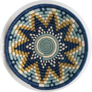 The Sunrise Handwoven Basket by Her Best Foot Forward features blue, beige, white, and light green concentric circles and geometric patterns. Made from sweet grass in East Africa, this symmetrical lid is perfect for unique wall or table decor.