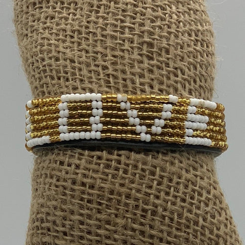 The Share the LOVE Beaded Bracelet by Her Best Foot Forward features white beads spelling LOVE among gold beads—a meaningful, handmade Maasai jewelry piece from East Africa, perfect as a unique and thoughtful gift.