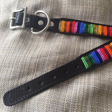 Load image into Gallery viewer, The Her Best Foot Forward Ethan Almighty Beaded Dog Collar—an ethical, handmade East African accessory—features colorful Maasai beadwork on black leather with a silver buckle and ring, displayed on beige textured fabric.