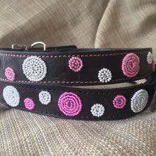 Load image into Gallery viewer, A close-up of two Petunia Pink Beaded Dog Collars by Her Best Foot Forward, handmade in East Africa, showcases pink and white bead patterns on dark leather, resting on textured beige fabric.