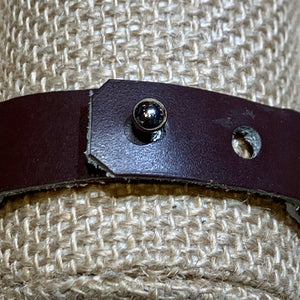 Close-up of the Safari Stripes Beaded Bracelet by Her Best Foot Forward, handmade Maasai jewelry from East Africa with alternating stripes, shown on textured beige woven fabric. Strap has a metallic stud fastener; one hole is slightly frayed.