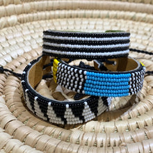 Load image into Gallery viewer, The Safari Stripes Beaded Bracelet by Her Best Foot Forward features handmade Maasai beadwork with black, white, blue, and yellow stripes and a leather lining, highlighting East African artistry.