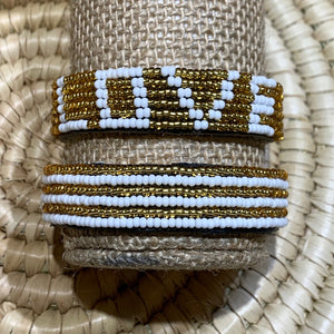 The Share the LOVE Beaded Bracelet by Her Best Foot Forward is handmade Maasai jewelry from East Africa, featuring white and gold beads that spell “LOVE”—a meaningful gift for someone special.
