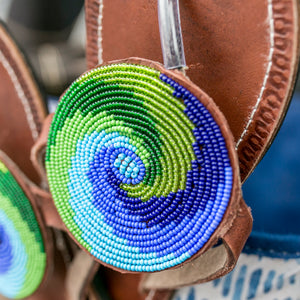 Close-up of Her Best Foot Forward’s Ocean Wave Handmade Beaded Sandals, showcasing ethical Maasai beadwork in green, blue, and white spirals for a coastal-inspired accent.