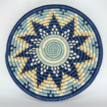 Load image into Gallery viewer, The Sunrise Handwoven Baskets by Her Best Foot Forward feature intricate, star-like blue, cream, and beige patterns. Crafted in East Africa from sweet grass, these round lids make stunning wall or table decor.