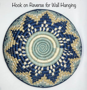 The Sunrise Handwoven Baskets by Her Best Foot Forward are round sweet grass trays from East Africa with a blue, beige, and cream star pattern. Hook on reverse for wall hanging—perfect as unique decor or an African basket display.