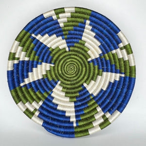 The Sunrise Handwoven Basket Lid by Her Best Foot Forward features a geometric spiral pattern in green, blue, and white—handcrafted from sweet grass in East Africa. Perfect as unique wall or table decor.