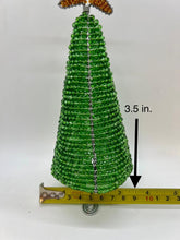 Load image into Gallery viewer, The 3.5 Hand-Beaded Christmas Tree by Her Best Foot Forward is handcrafted in Tanzania from reclaimed wire, featuring festive decorations and topped with a gold ornament. A measuring tape highlights its small, conical shape.