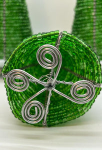 Close-up of the base of a Hand-Beaded Christmas Tree by Her Best Foot Forward—crafted from green beads and reclaimed wire in Tanzania, featuring circular forms with four spiral designs, handmade by women artisans.
