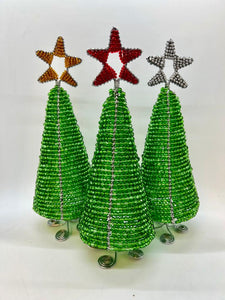 Three Hand-Beaded Christmas Trees by Her Best Foot Forward, crafted from reclaimed wire in Tanzania, each feature a spiral base and a gold, red, or silver star. These handmade holiday decorations are displayed against a plain white background.