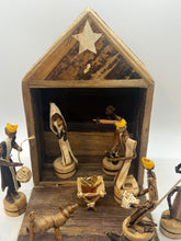 Load image into Gallery viewer, The Handmade Nativity Set by Her Best Foot Forward is a fair wage Christmas decor from Tanzania, featuring Mary, Joseph, baby Jesus in a manger, three wise men with gifts, an angel, and a donkey inside a rustic stable with star.
