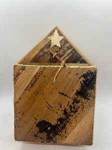 The Handmade Nativity Set by Her Best Foot Forward is a rustic wooden box with a slanted lid, carved white star, and string-tied stick. Made in Tanzania using worn wood, it adds authentic charm to your Christmas decor and supports fair wages.