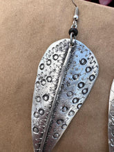 Load image into Gallery viewer, The Chuma Etched Metal Earrings by Her Best Foot Forward are lightweight, silver-toned leaf-shaped earrings with zigzag and circular patterns, handmade in East Africa and shown against a plain brown background.