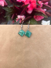 Load image into Gallery viewer, The Kijani Malachite Square Earrings by Her Best Foot Forward, handmade green stone jewelry from East Africa, rest on a brown surface with blurred pink and dark red flowers in the background.