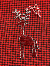 Load image into Gallery viewer, The Reindeer Friends ornament by Her Best Foot Forward is a handcrafted, beaded holiday decoration from Tanzania featuring detailed antlers and a hanging loop, displayed on red and black checkered fabric.