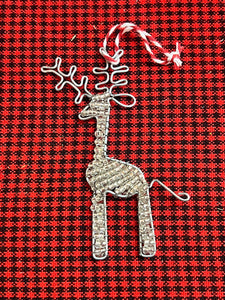 The Reindeer Friends ornament by Her Best Foot Forward features handcrafted beads and hangs from a twisted red and white string, set against a red and black plaid fabric—capturing the spirit of Tanzanian holiday decorations.