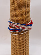 Load image into Gallery viewer, The Shanga Slide Beaded Bracelet by Her Best Foot Forward features easy slip-on Maasai-inspired red, white, blue, and silver beads stylishly wrapped on a display stand.
