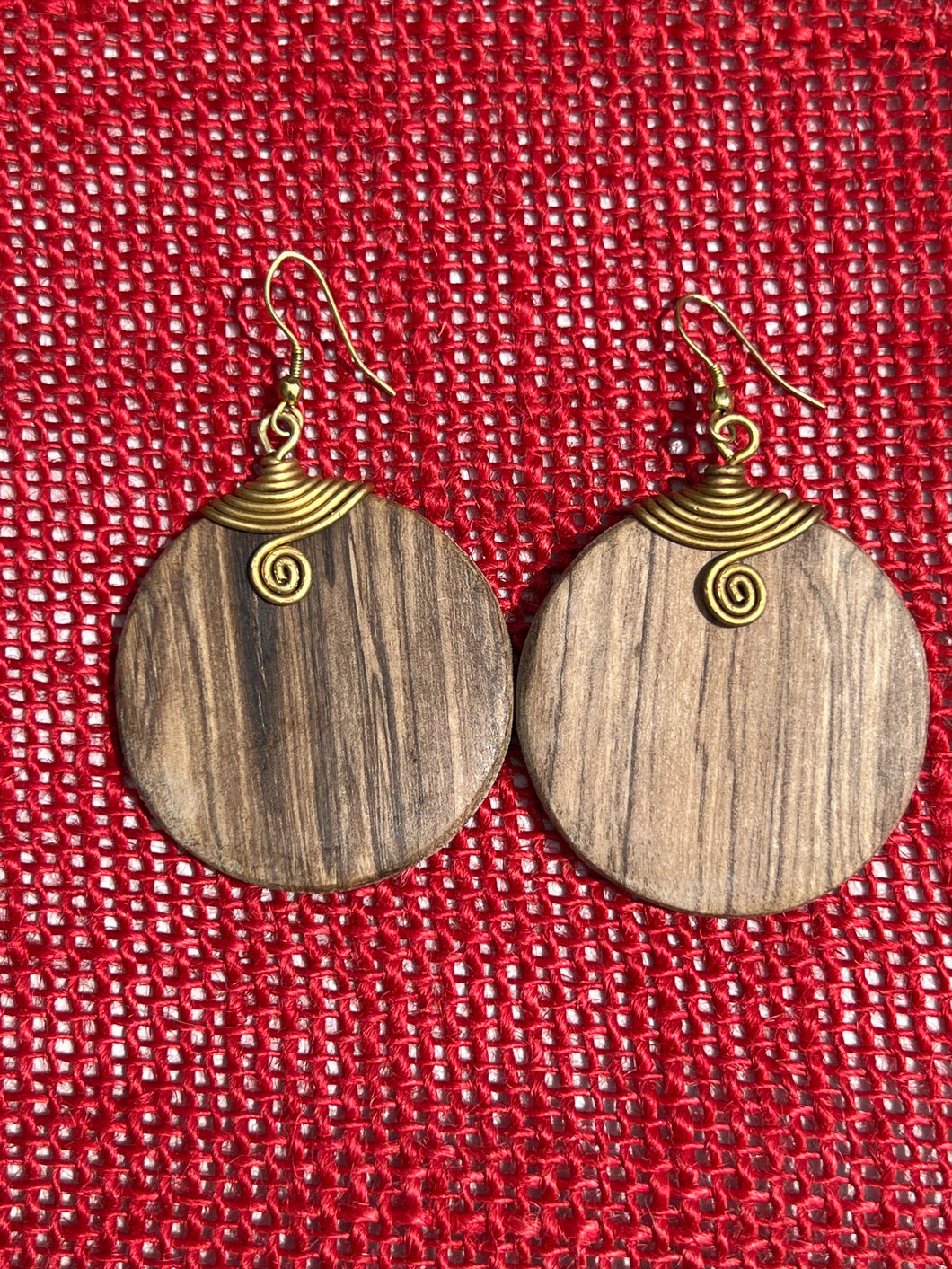 Rosemiti Hand-Carved Rosewood Earrings by Her Best Foot Forward feature brass accents and a statement design inspired by East Africa, displayed against a textured red background.