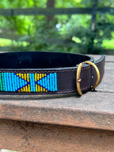 Load image into Gallery viewer, The Proud as a Peacock beaded dog collar by Her Best Foot Forward, handmade in East Africa with vibrant Maasai beadwork, is displayed on a wooden surface outdoors.