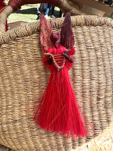The Angels From On High - Handcrafted Fiber Christmas Ornaments from Tanzania by Her Best Foot Forward feature a red angel with straw-like wings, a small harp, and detailed natural fiber accents, handmade by Tanzanian women artisans.