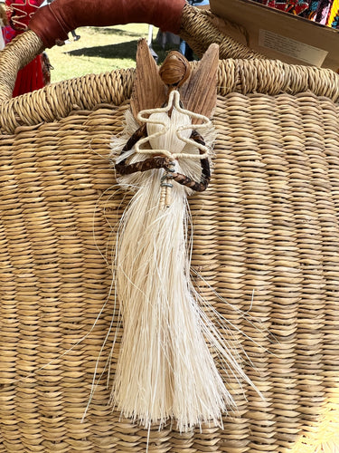 The Angels From On High ornament by Her Best Foot Forward is handcrafted in Tanzania, featuring a wooden body, straw fiber skirt and wings, made by women artisans and presented against a woven straw basket.