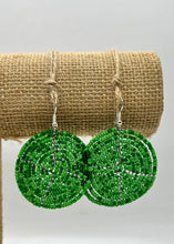 Load image into Gallery viewer, The Duara Circular Beaded Earrings by Her Best Foot Forward, handmade Maasai statement jewelry from East Africa, feature round green beads with peace sign designs and are displayed on twine against a white background.