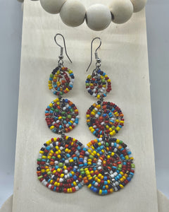 The Kiungo Conjoined Circle Earrings by Her Best Foot Forward feature three colorful Maasai beaded circles hanging from silver hooks, topped with large wooden beads—unique handmade statement jewelry from East Africa.